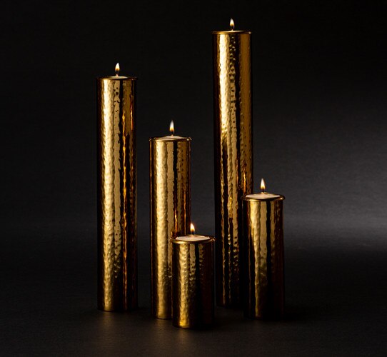 Hammered polished brass candle holders of various height with lit candles inside