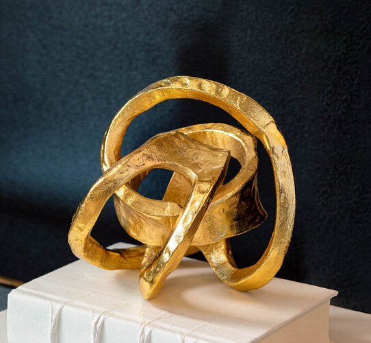 Knotted gold sculpture resting on a white book