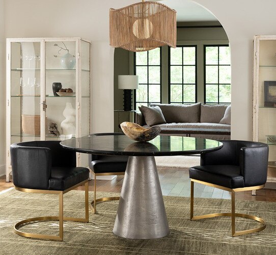 Circular dining table with black leather chairs and a horn bowl in the center