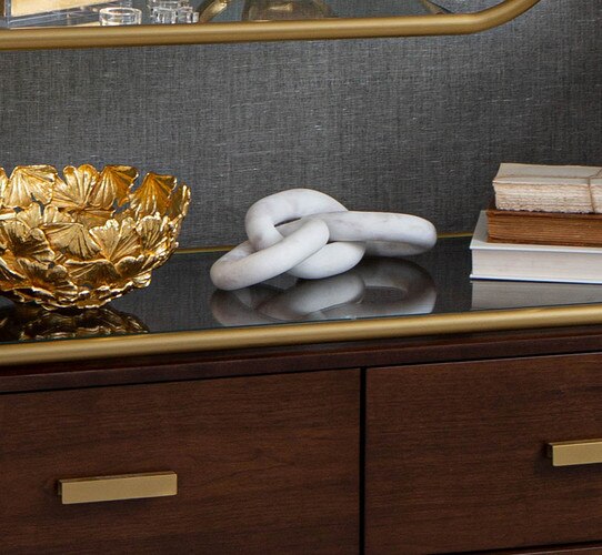 Marble chains between a gold bowl and books stacked atop a wood console table