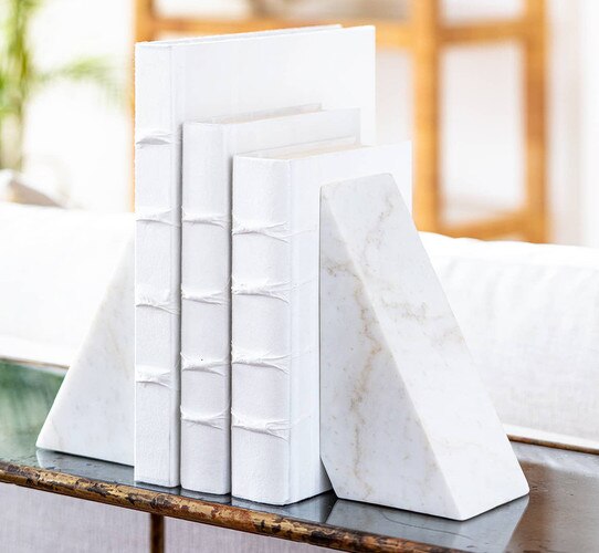 White marble bookcases holding up three white books