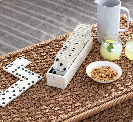 Bone domino set beside a bowl of peanuts and two glasses of lemonade