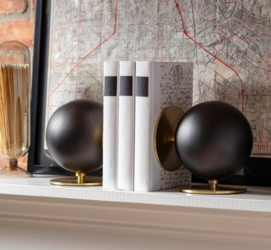 Black and brass circular bookends holding up books on a shelf