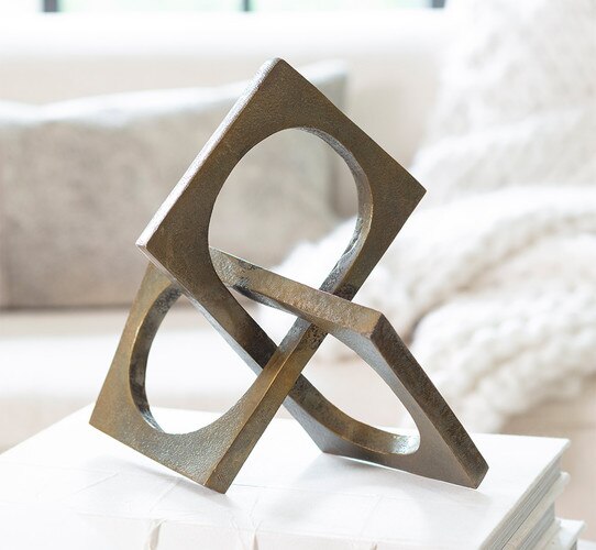 Intersecting square brass sculpture resting on a white book