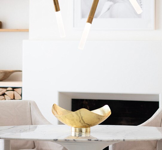 Brass metal bowl resting in the center of a white marble dining table