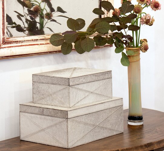 Two hair on hide boxes beside a ceramic vase