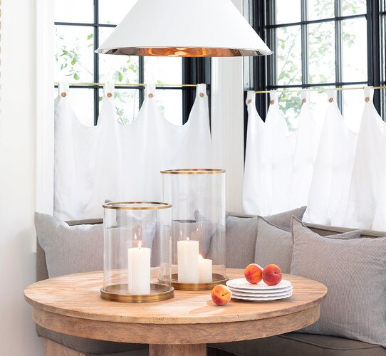 Glass hurricanes with brass accents on a circular wood table