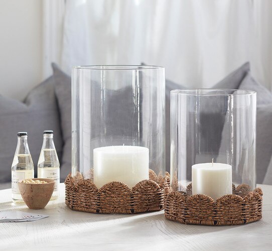 Wood table holding a woven hurricane and two bottles of water