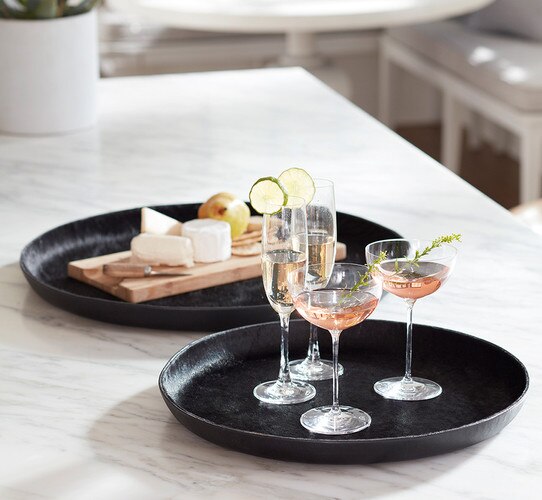 Two hair on hide trays with cocktail glasses and a charcuterie board