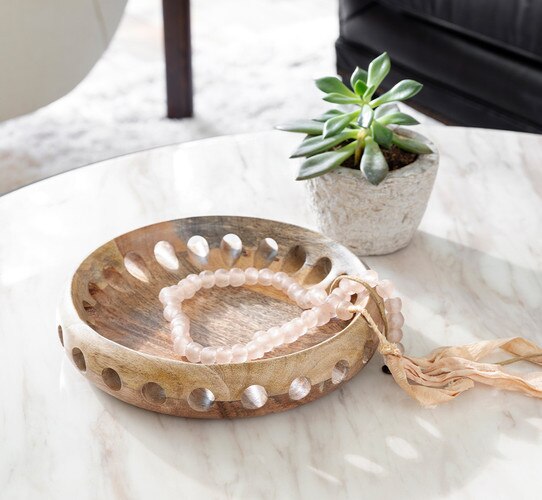 Wood bowl holding a beaded necklace next to a succulent