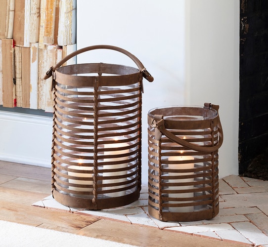 Leather hurricane holders beside a fireplace