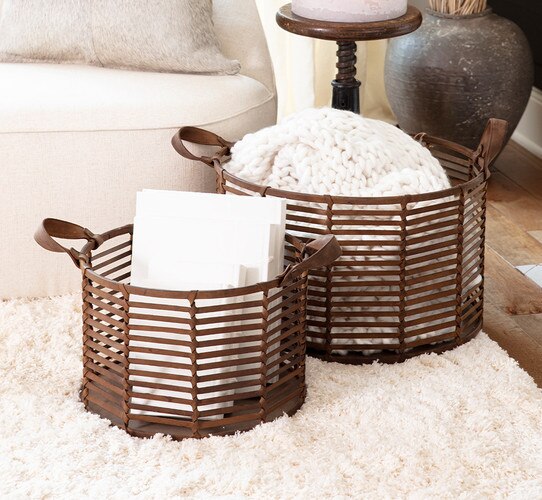 Leather baskets holding blankets and books on a white rug