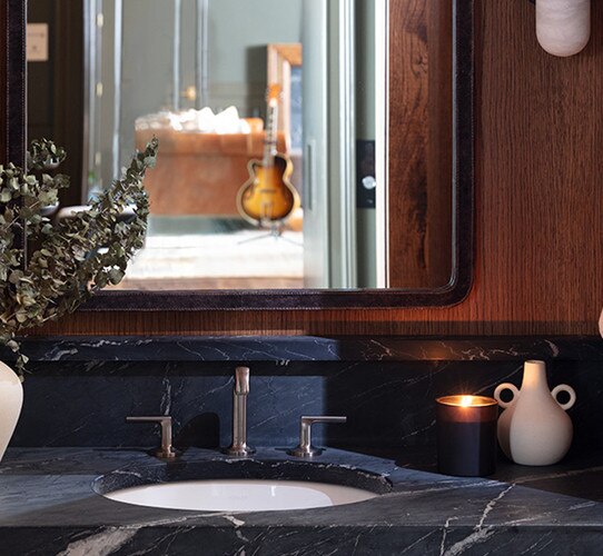 Marble sink holding a candle and vase in a bathroom