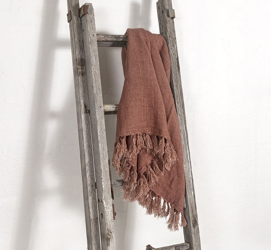 Antique wooden ladder with a red throw draped over the top