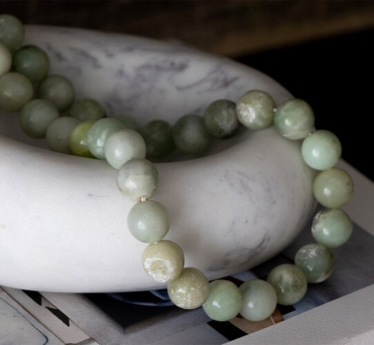 White marble bowl holding green beads