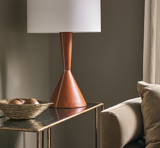 Console table holding a leather lamp and decorative gold bowl