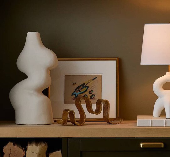 Shelf with white sculpture and metal wave sculpture