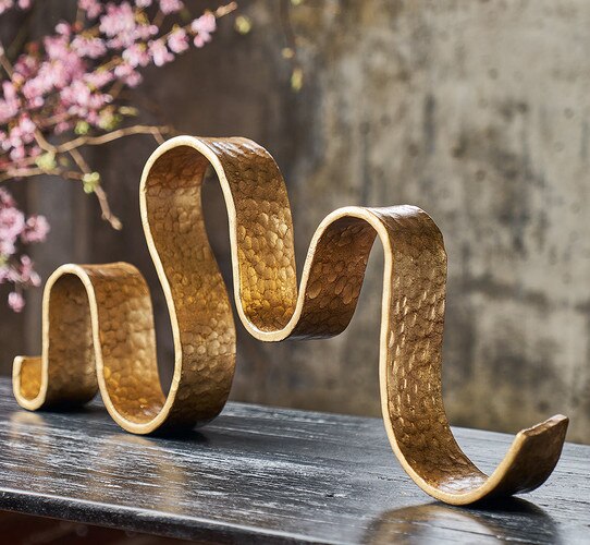 Brass ribbon sculpture on wood table