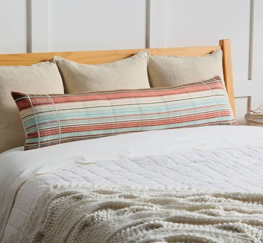 White bed spread with long multi colored bolster pillow