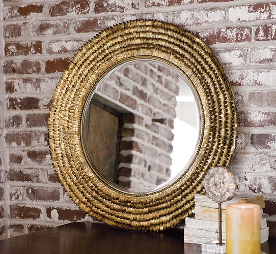 Flower petal mirror resting on a wooden table against a brick wall