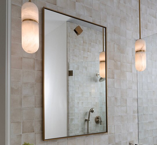 Rectangular brass mirror on a tile wall with alabaster pendants hanging to the left and right