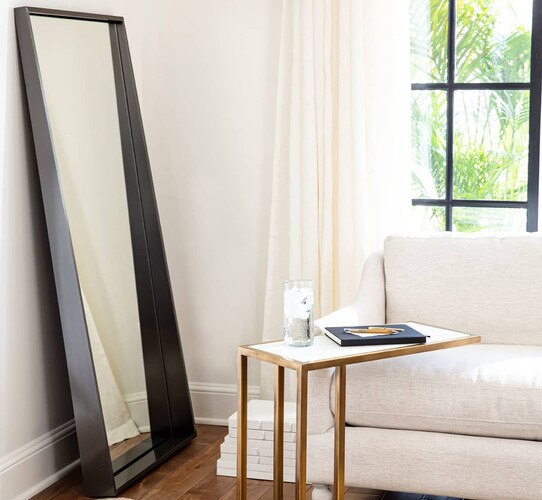 Black full length mirror beside white sofa