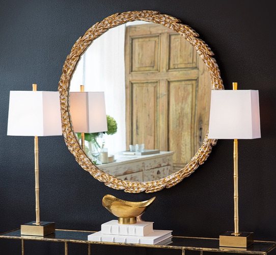 Gold olive branch mirror hung between two gold buffet lamps