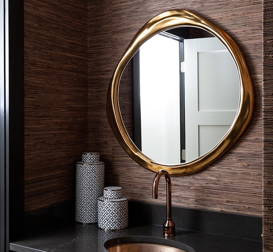 Organically shaped gold mirror above a kitchen sink