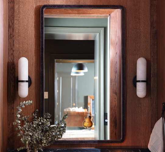 Leather framed mirror above a bathroom sink