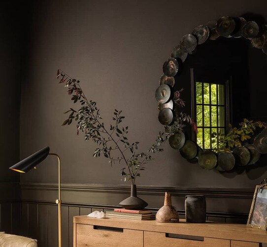 Black round mirror above wood dresser