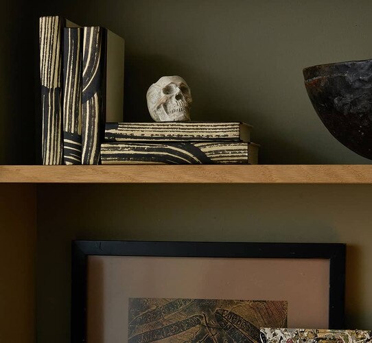 Black and gold decorative books holding a small stone skull