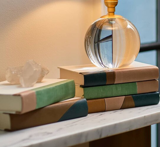 Multi colored leather bound books holding crystal table lamp