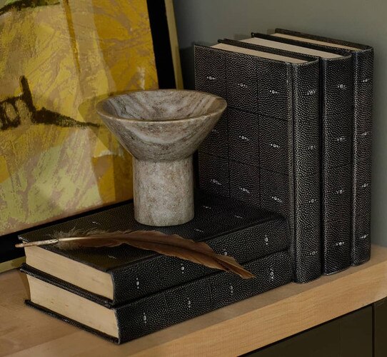 Leather-bound books holding a stone bowl