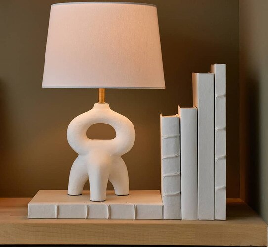 White modern lamp on top of a white book with four more to the side of it