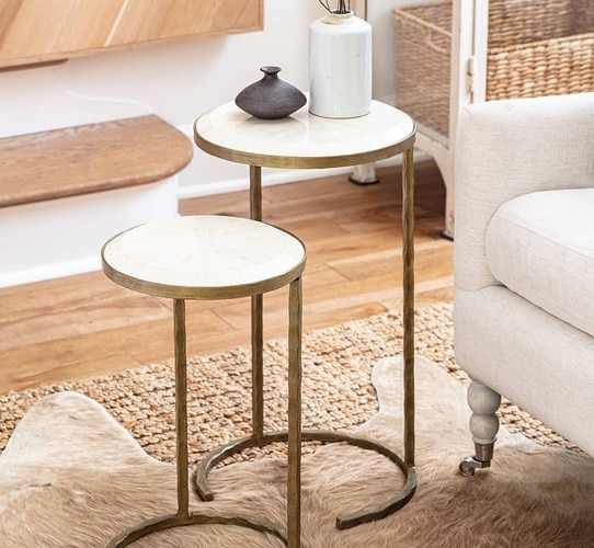 Bone and brass nesting side tables beside a white sofa