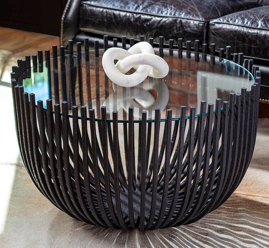 Black webbed coffee table with glass top holding a marble sculpture
