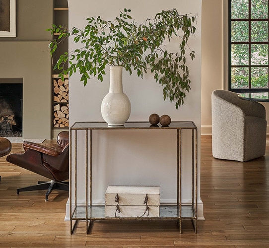 Metal console table holding a large vase with foliage