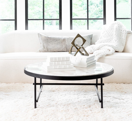 White and black coffee table holding books and brass sculpture
