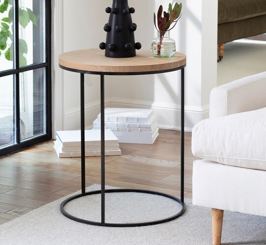 Circular wooden side table beside a white sofa