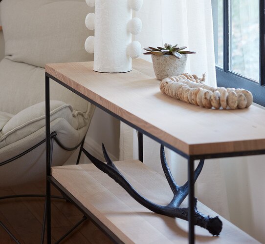 Long metal and wood console table holding a lamp and an antler