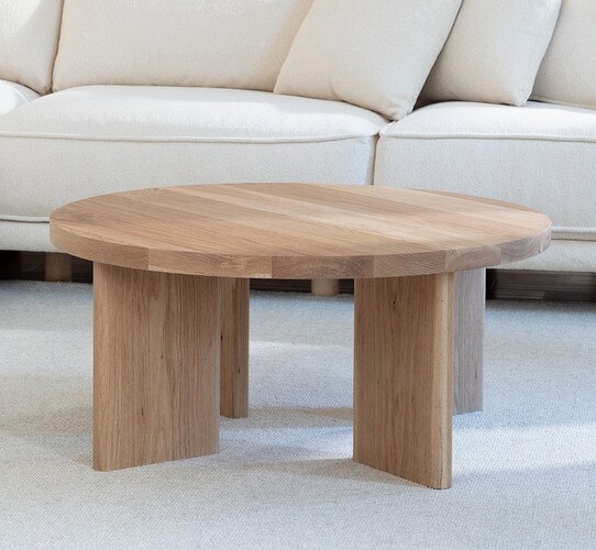 Circular wood coffee table in front of a white sofa