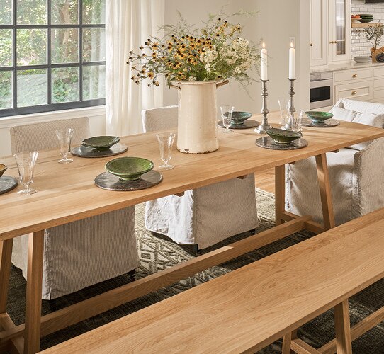 Wood dining table with green place settings and jar of flowers