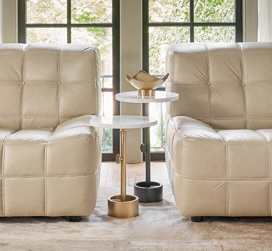 Two metal and marble side tables between two leather accent chairs
