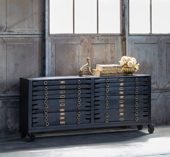 wooden console with drawers holding books and a sculpture