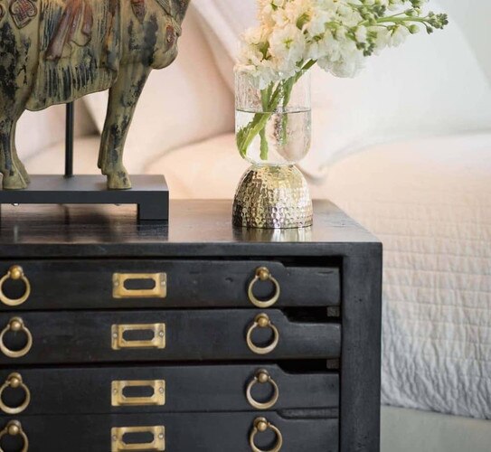 Black and brass nightstand with a horse lamp and small vase