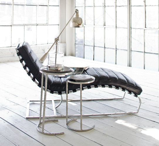 Black and metal chaise lounge beside a set of nesting tables