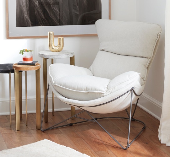 White linen chair beside three brass nesting tables