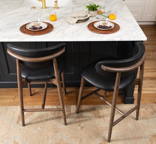 Marble kitchen island with two plates, glasses, and two black leather stools
