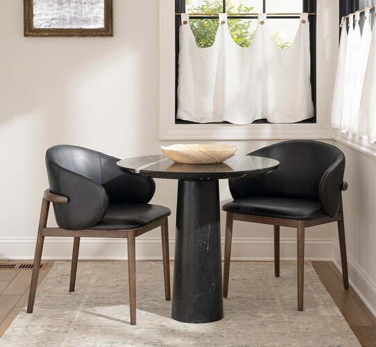 Breakfast nook with a black pillar table and two black leather dining chairs