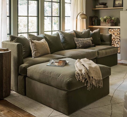 Green sectional sofa with a throw blanket over the chaise